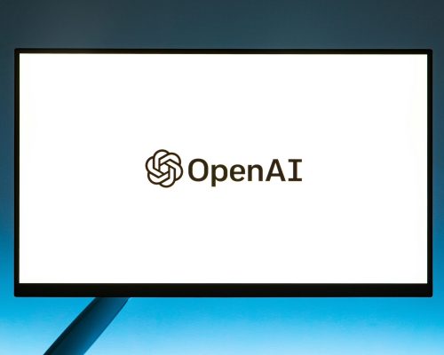 Minimalistic display of OpenAI logo on a monitor with a gradient blue background, representing modern technology.